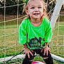 child, toddler, soccer_ball, soccer_goal, green_shirt, pink_shoes, hair_bows, outdoor, grass, sports, smiling, happy, playing, net, field, cute, young_child, athletic, recreation, active