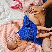 Zahara joined the competition — help win amazing prizes! baby, blue_dress, pink_blanket, infant, child, person, hand, nail_polish, adult, soft_texture, bed, relaxing, cute, lying_down, tender_moment, skin, blanket, comfort, family, indoor