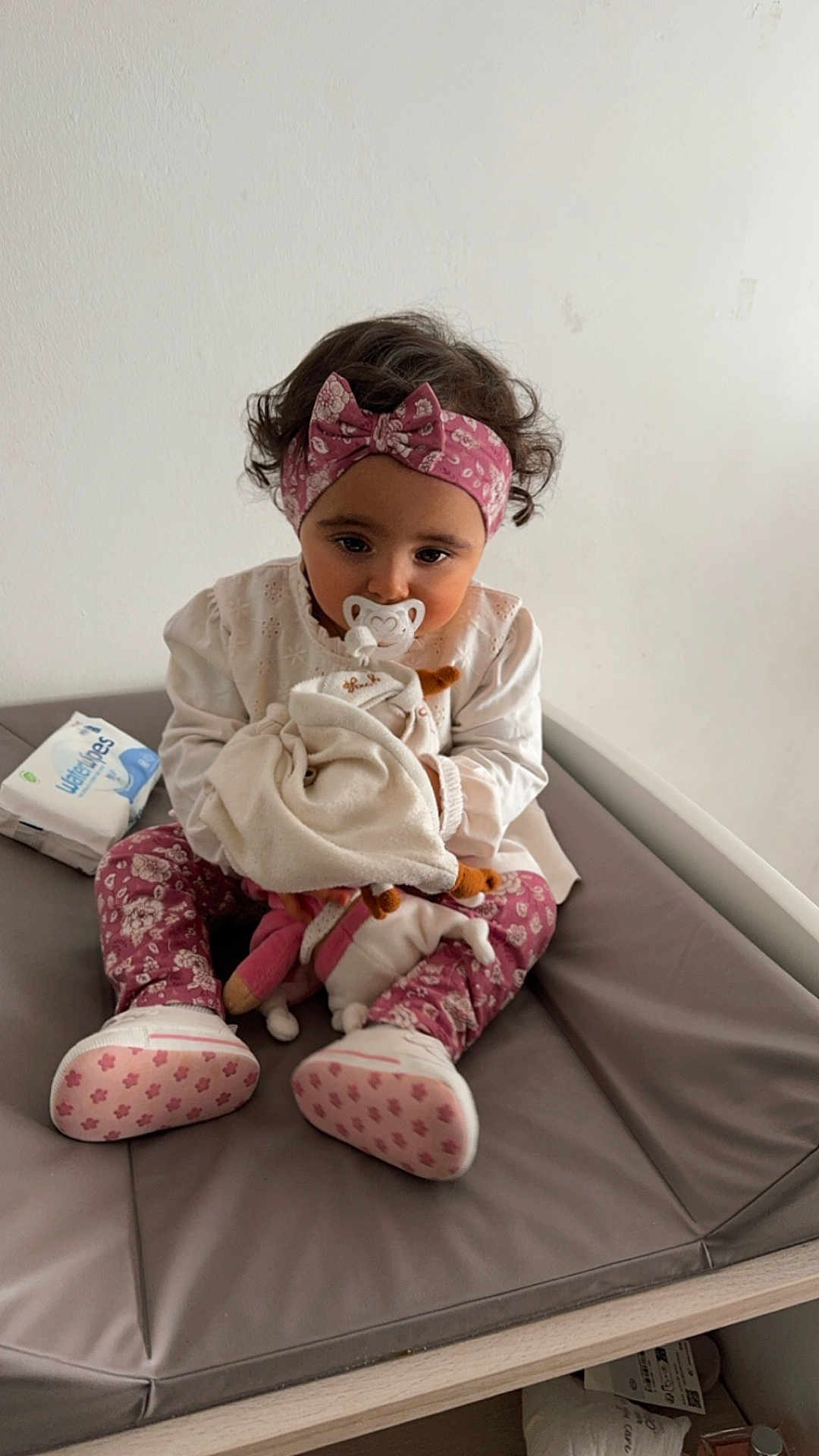Jannah participe au concours pour gagner de l'argent avec cette photo : baby, baby_wipes, blanket, changing_table, child, clothing, cute, floral_pattern, footwear, headband, indoor, pacifier, person, pink, sitting, soft_toy, toddler, toy, white, young_child