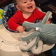 Aydan is registered to the contest to win money with this photo: baby, child, smiling, red_clothing, plush_toy, octopus_toy, baby_walker, happy, infant, indoors, seat, toy, feet, hands, floor, wood_floor, cute, cheerful, person, playtime