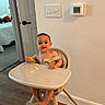 baby, high_chair, food, smiling, indoor, wooden_floor, door, bedroom, baby_food, child, person, modern_furniture, wall, thermostat, light_switch, happy, cute, infant, home, casual
