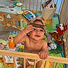 baby, child, playpen, toys, diaper, cap, indoor, colorful, basket, stuffed_animal, floor_mat, wooden_bars, smiling, cute, play, infant, happy, person, home, baby_toys