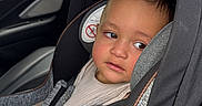 Derian is registered to the contest to win money with this photo: toddler, child, car_seat, car_interior, seat_belt, gray, black, beige_clothing, safety, vehicle, window, side_view, young_child, baby, seat, restraint, indoors, transportation, person, portrait