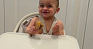 Derian is registered to the contest to win money with this photo: baby, high_chair, food, smile, indoor, wooden_floor, door, child, infant, happy, feeding, modern_furniture, person, cute, toddlers, seat, home, young_child, skin, head