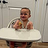 Derian is registered to the contest to win money with this photo: baby, high_chair, food, smile, indoor, wooden_floor, door, child, infant, happy, feeding, modern_furniture, person, cute, toddlers, seat, home, young_child, skin, head