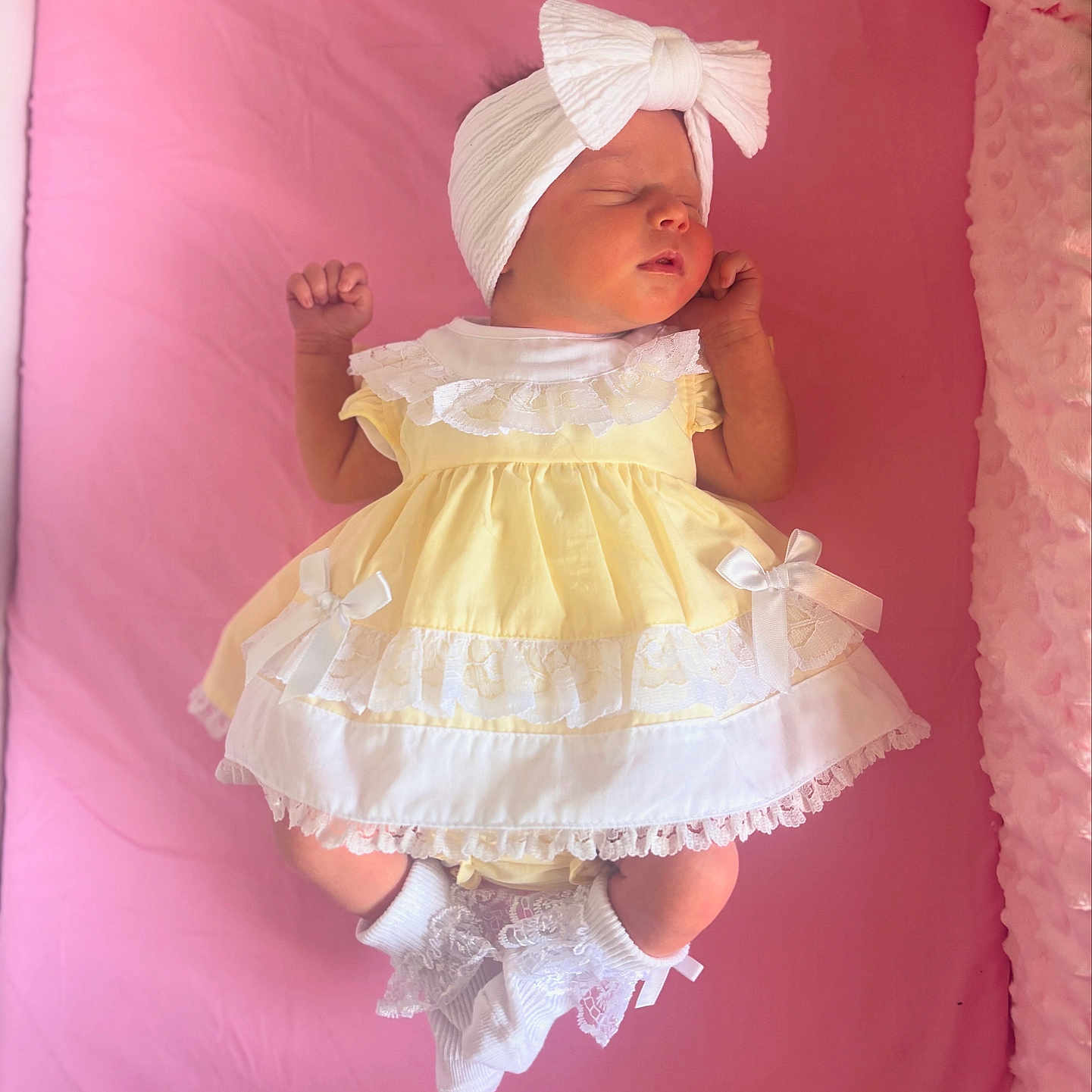 Mýa-Rae is registered to the contest to win money with this photo: adorable, baby, bow, child, cute, dress, headband, indoors, infant, lying_down, newborn, peaceful, pink_blanket, portrait, resting, sleeping, socks, soft, white, yellow