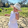 Olive joined the competition — help win amazing prizes! toddler, child, white_dress, sunhat, flower, daisy, park, grass, trees, spring, sunlight, stone_path, outdoor, nature, people_in_background, greenery, smiling, happy, person, daylight