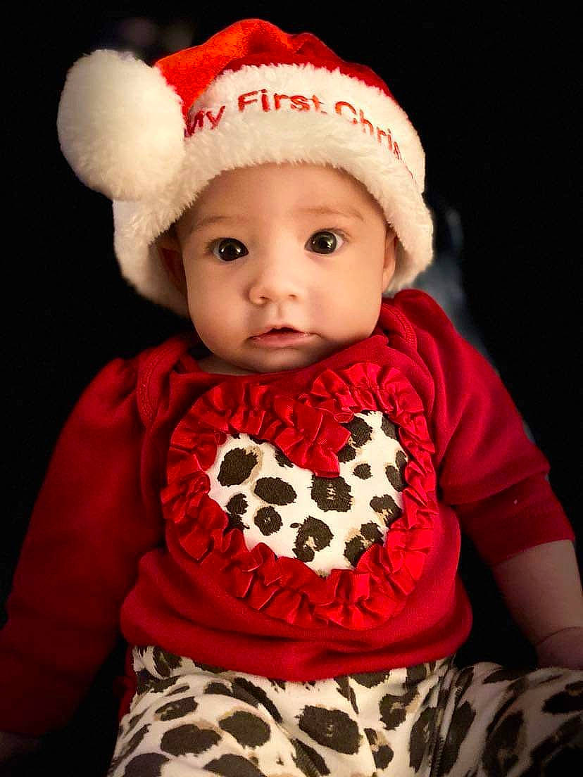 Cali is registered to the contest to win money with this photo: baby, baby_toddler_clothing, black, cap, child, costume_hat, dress, hat, head, headgear, headwear, human_body, lip, organ, outerwear, pattern, person, red, sleeve, t_shirt