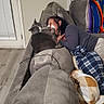 Boots is registered to the contest to win money with this photo: cat, person, couch, blanket, paw, face, indoor, window, curtain, floor, home, relaxing, pet, gray_cat, plaid_blanket, cozy, affection, resting, living_room, casual