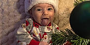 Miller joined the competition — help win amazing prizes! baby, child, christmas, holiday, festive, santa_hat, pajamas, blanket, tree, ornament, tongue_out, smiling, cute, celebration, indoors, face, infant, seasonal, cozy, joyful