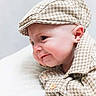 baby, infant, child, face, headwear, cap, shirt, clothing, pattern, houndstooth, cute, portrait, closeup, skin, ear, button, lying_down, soft_surface, expression, curious