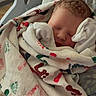 newborn, baby, blanket, hospital, bassinet, sleeping, infant, footprint_pattern, wrapped, cozy, face, head, peaceful, soft_light, indoors, healthcare, resting, clothing, person, portrait