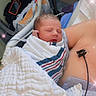 newborn, baby, hospital, blanket, swaddled, sleeping, person, medical_equipment, chest, skin, chair, phone, bag, sparkles, closeup, indoor, comfort, rest, tenderness, care