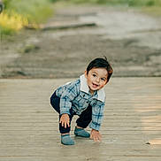 Marcello joined the competition — help win amazing prizes! toddler, child, outdoor, wooden_path, plaid_jacket, socks, smiling, crouching, happy, nature, daylight, portrait, casual_clothing, cute, young_child, playful, person, scenic, greenery, fun