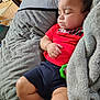 baby, sleeping, child, cushion, blanket, red_shirt, shorts, toy, indoor, peaceful, resting, cozy, soft_texture, furniture, home, infant, comfort, portrait, relaxing, cute