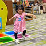 toddler, child, pink_dress, play, library, bookshelves, floor_tiles, indoor, person, sneakers, carpet, colorful, motion, fun, happy, young_child, curly_hair, education, reading_area, adult