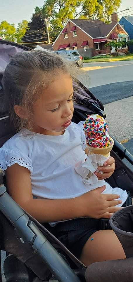 Maliyah is registered to the contest to win money with this photo: baby, blond, chair, child, dairy, dessert, event, facial_expression, food, fun, hairstyle, hat, head, ice_cream, ice_cream_cone, mammal, person, shorts, sitting, t_shirt