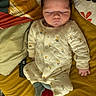 Lio a rejoint le concours — aidez-le/la à gagner de superbes lots ! baby, infant, sleeping, onesie, floral_pattern, bed, pillow, blanket, remote_control, socks, yellow, red, green, indoor, cozy, cute, peaceful, person, child, nap