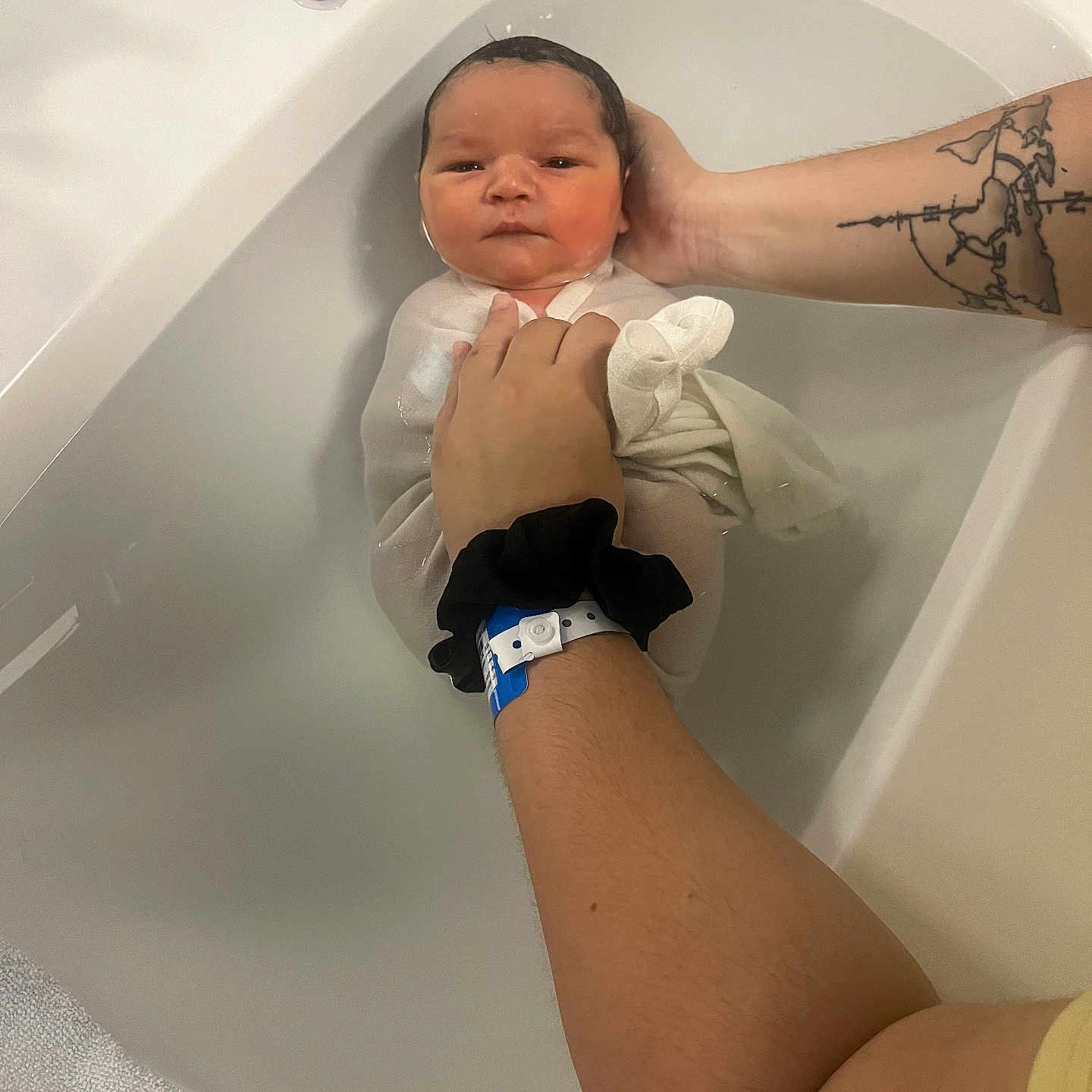 Lio participe au concours pour gagner de l'argent avec cette photo : newborn, baby, bath, water, arm, tattoo, cloth, towel, thermometer, infant, person, white, skin, hand, face, expression, support, container, indoor, care
