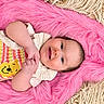 baby, infant, child, smiling, lying_down, portrait, face, eyes, hands, knitted_clothing, yellow_character, pink_blanket, furry_blanket, beige_blanket, textile, indoor, close_up, happy, adorable, photography