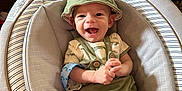 Jasper joined the competition — help win amazing prizes! baby, smiling, green_hat, green_outfit, baby_seat, cushion, infant, happy, indoor, wooden_furniture, portrait, child, clothing, cute, sitting, expression, face, small_hands, legs, comfortable
