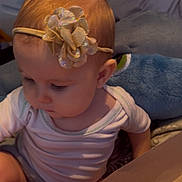 Kinsley is registered to the contest to win money with this photo: baby, blanket, child, clothing, curious, cute, eyelashes, face, flower, hair, headband, indoor, infant, person, pink, seated, skin, soft_toy, toddler, white_shirt