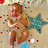 Rylan is registered to the contest to win money with this photo: baby, blanket, celebration, child, confetti, feet, fourth_of_july, hands, happy, holiday, indoor, infant, lying_down, onesie, patriotic, photography, portrait, red_white_blue, smiling, star_sign