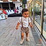 toddler, child, boy, walking, shorts, suspenders, white_shirt, shoes, outdoor, event, people, seated, glass_railing, reflection, mountains, cityscape, wooden_floor, daylight, curious, cute