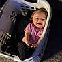 Lilith joined the competition — help win amazing prizes! baby, child, laundry_basket, carpet, pink_shirt, black_pants, slippers, smiling, happy, indoors, person, cute, relaxed, playing, cozy, curly_hair, toddler, home, seat, hands