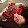 blanket, carpet, child, comfort, cozy, cute, face, happy, head, home, indoor, lying_down, pajamas, person, plaid, smiling, soft_focus, toddler, warm, young_child