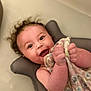 Lilith is registered to the contest to win money with this photo: baby, blanket, blue_eyes, child, curly_hair, cushion, cute, expression, face, hand, happy, holding, indoors, infant, lying_down, playful, portrait, skin, smiling, toddler