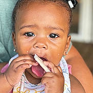 Emmery joined the competition — help win amazing prizes! toddler, child, baby, face, hands, food, bib, pigtails, snack, mouth, tongue, curious, closeup, person, infant, cute, eating, indoor, portrait, colorful_bib