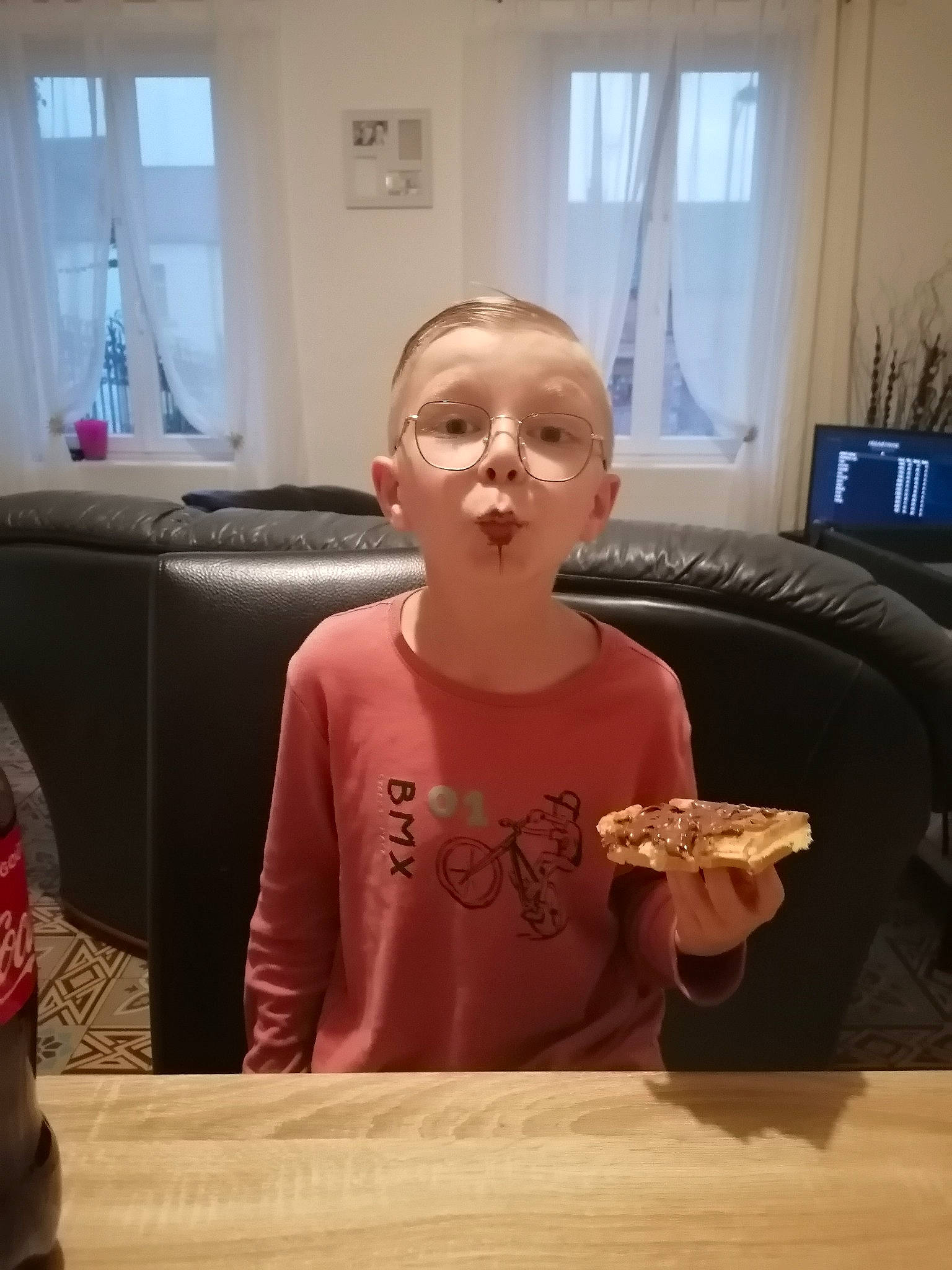 Mathias Mael participe au concours pour gagner de l'argent avec cette photo : breakfast, carbonated_soft_drinks, chair, child, cola, comfort_food, curtain, drink, eating, flooring, fun, person, room, sitting, soft_drink, t_shirt, table, tableware, tin_can, toddler