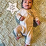 baby, infant, blanket, onesie, star_shaped_sign, milestone, lying_down, indoor, cute, portrait, face, hands, feet, text, milestone_marker, cozy, soft_texture, expression, young_child, newborn