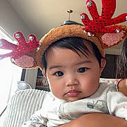 Maliah is registered to the contest to win money with this photo: baby, child, reindeer_headband, holiday, festive, cute, indoor, person, face, hand, clothing, arm, looking, expression, cozy, holiday_accessory, infant, holding, cute_outfit, portrait