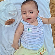 Halley a rejoint le concours — aidez-le/la à gagner de superbes lots ! baby, infant, towel, sand, cap, clothing, striped_top, shorts, outdoor, person, cute, smiling, face, head, skin, young_child, summer, relaxing, lying_down, casual