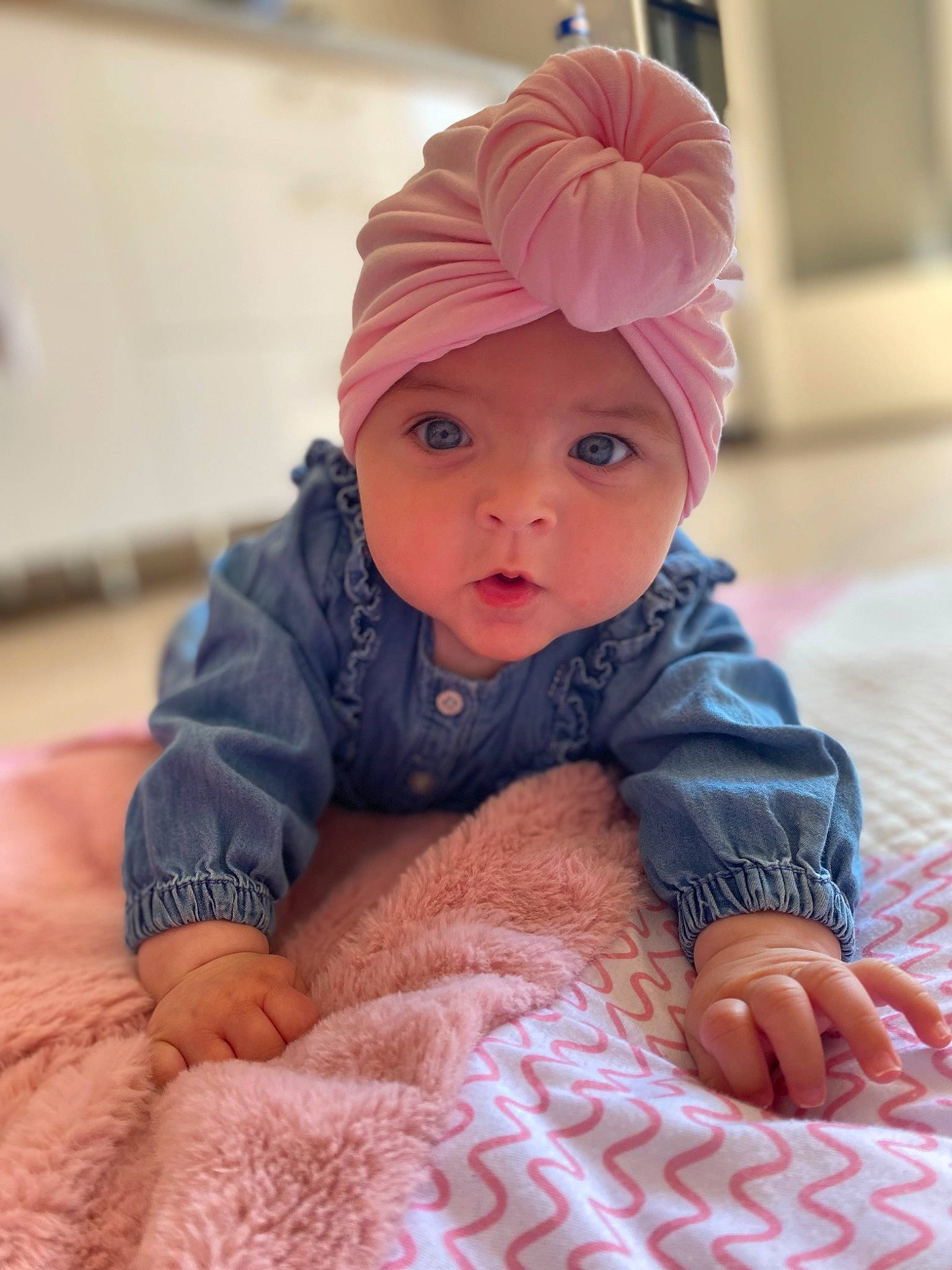 Ambre participe au concours pour gagner de l'argent avec cette photo : baby, baby_toddler_clothing, cap, cheek, child, comfort, eye, face, facial_expression, fashion_accessory, finger, flooring, headwear, magenta, outerwear, person, pink, sitting, skin, sleeve