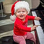 baby, child, piano, santa_hat, red_clothing, striped_pants, smiling, happy, indoors, music, musical_instrument, bench, holiday, christmas, cute, infant, playing, furniture, white_socks, floor