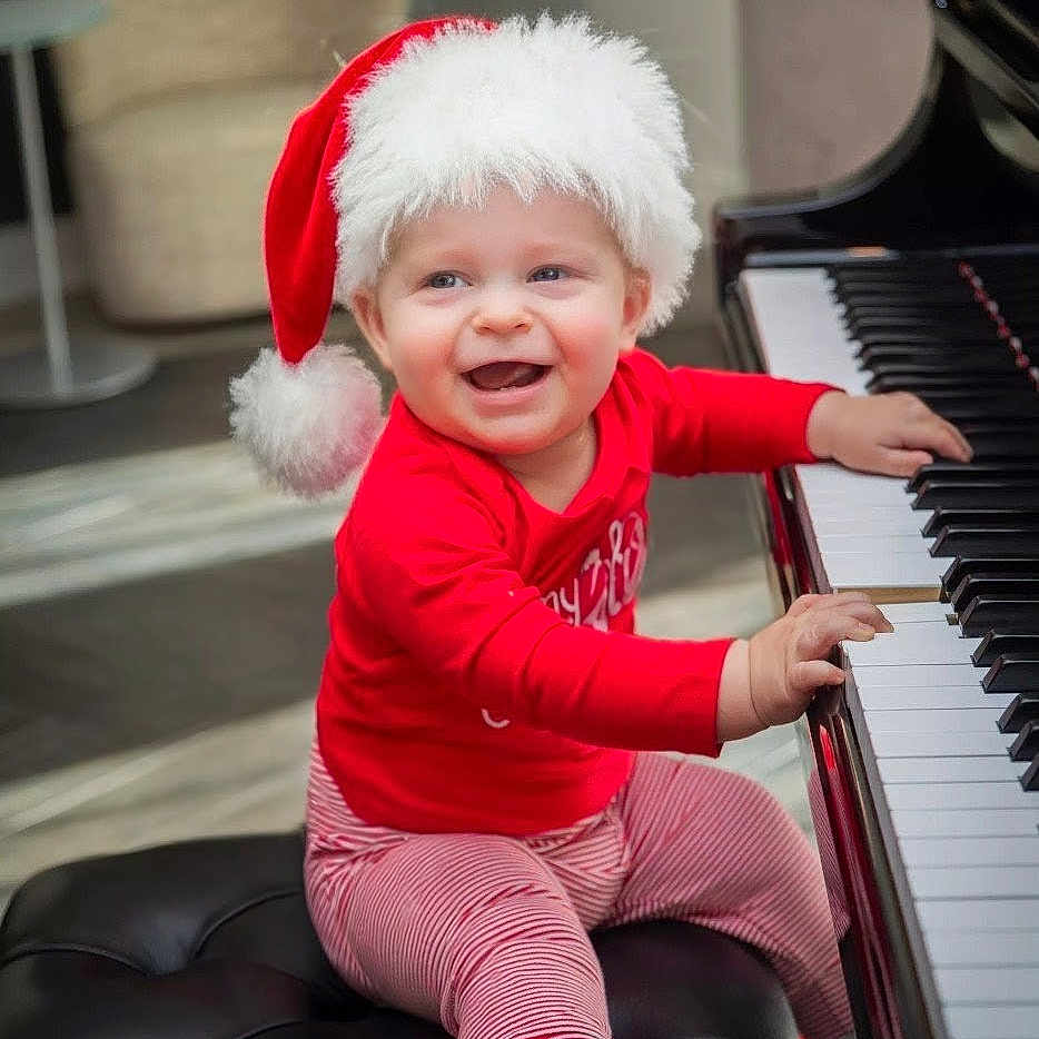 Graham joined the competition — help win amazing prizes! baby, bench, child, christmas, cute, floor, furniture, happy, holiday, indoors, infant, music, musical_instrument, piano, playing, red_clothing, santa_hat, smiling, striped_pants, white_socks
