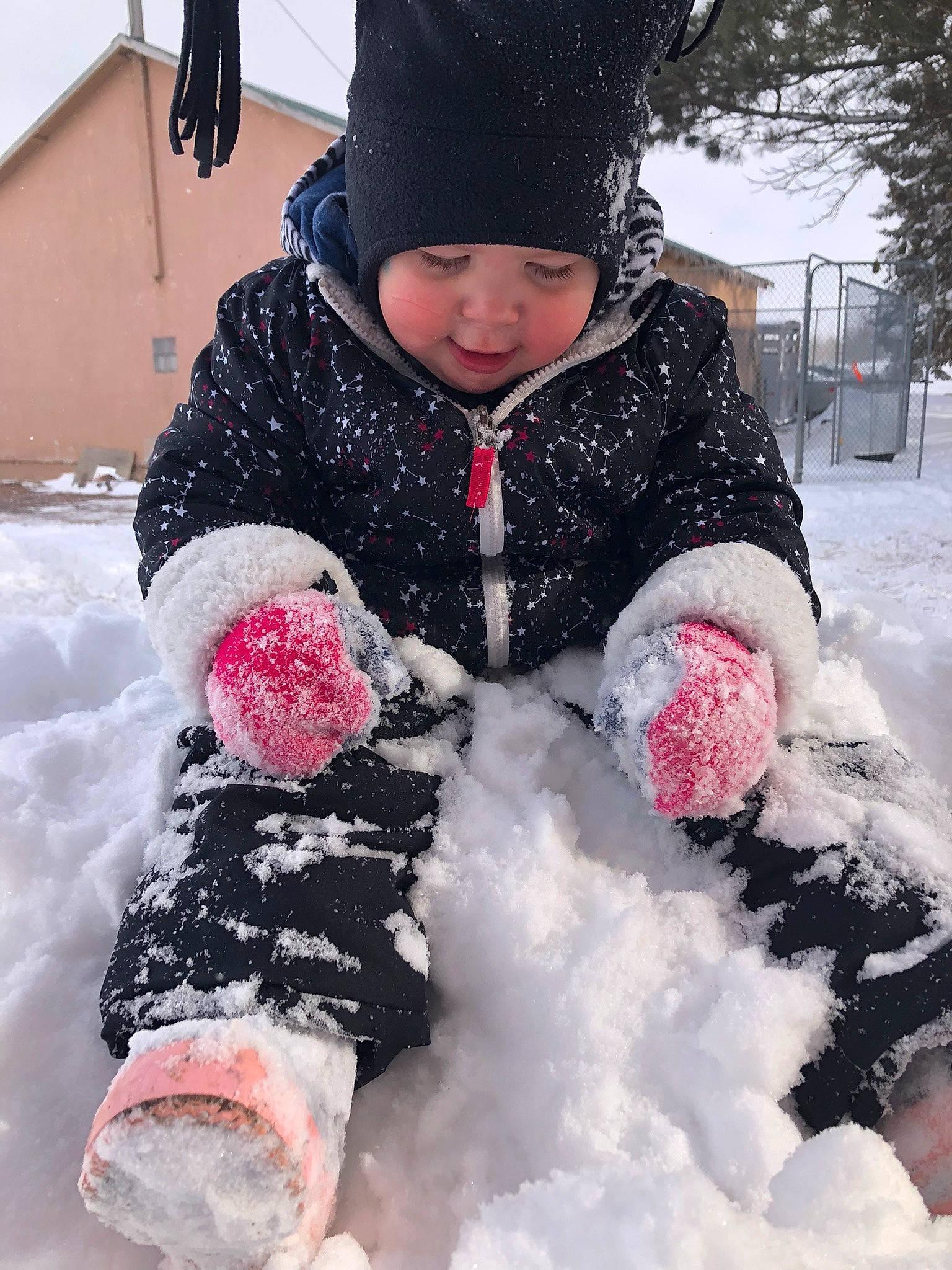 Bexley is registered to the contest to win money with this photo: cheek, child, event, freezing, fun, fur, headgear, headwear, jacket, knit_cap, parka, person, photograph, pink, playing_in_the_snow, precipitation, snapshot, snow, toddler, tree
