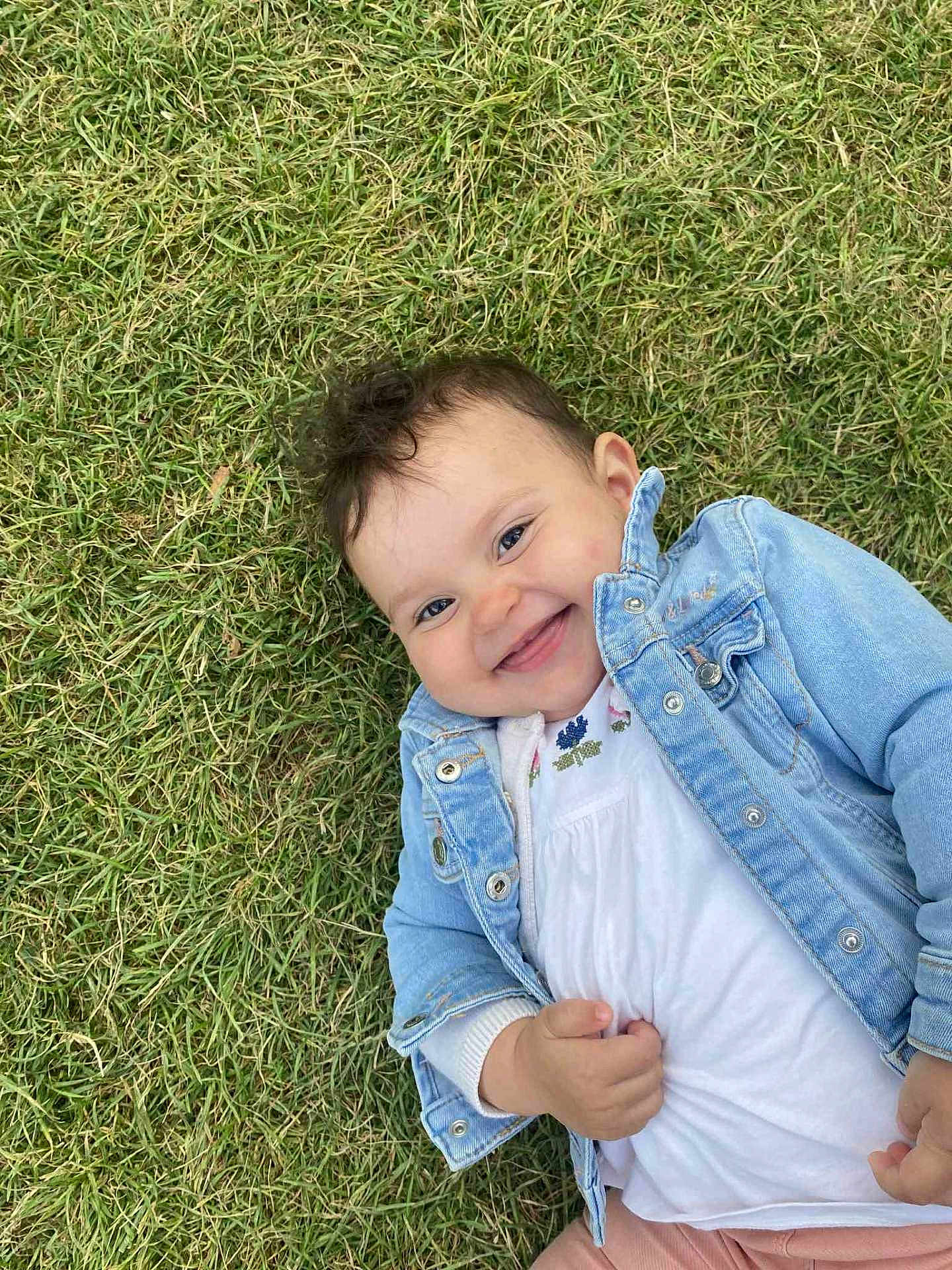 Ana-Maria a rejoint le concours — aidez-le/la à gagner de superbes lots ! baby, child, grass, smiling, denim_jacket, white_shirt, happy, outdoor, cute, young_child, portrait, nature, playful, person, casual_clothing, face, head, skin, baby_girl, lying_down
