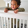 Lucas is registered to the contest to win money with this photo: baby, crib, smiling, child, indoor, bedroom, blanket, pajamas, furniture, wood, animal_decals, happy, infant, standing, handrail, cute, person, playful, toddler, home