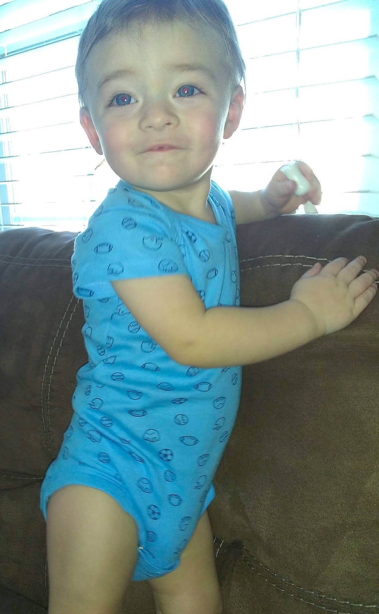 Kye is registered to the contest to win money with this photo: azure, baby_toddler_clothing, elbow, eye, face, finger, gesture, happy, head, human_body, joint, organ, person, shoulder, skin, sleeve, standing, thumb, toddler, window