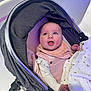 baby, stroller, blanket, smile, happy, child, infant, face, clothing, pink, white, hand, wheel, fabric, person, cute, cozy, indoors, head, eyelashes
