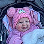 apparel, baby, baby_clothes, blanket, child, clothing, cozy, cute, face, happy, headwear, infant, outdoor, pink_hat, pom_poms, portrait, smiling, snuggled, stroller, warm