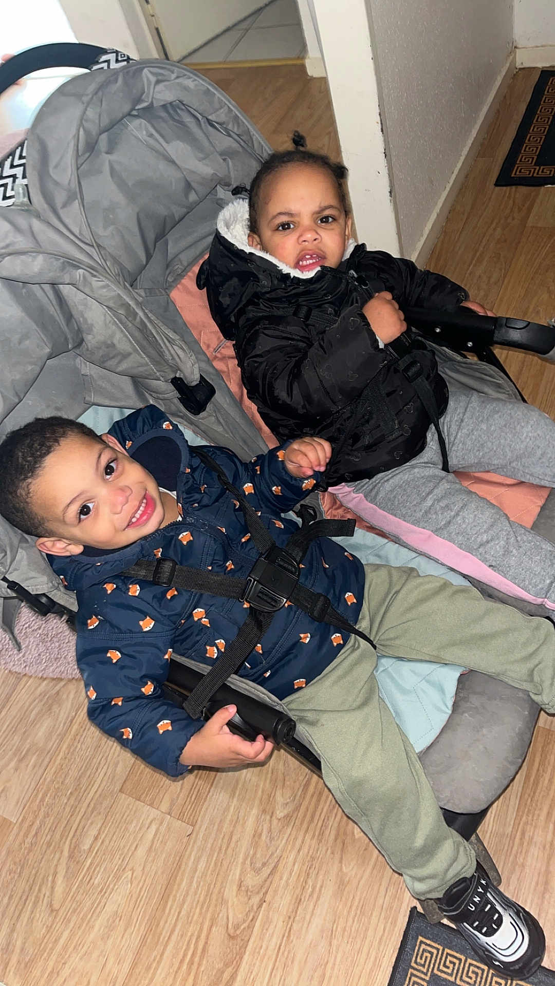 Kylian a rejoint le concours — aidez-le/la à gagner de superbes lots ! child, children, stroller, jacket, smile, indoor, floor, doorway, pants, shoe, happy, face, person, young, cute, seated, bundle_up, cozy, expression, home