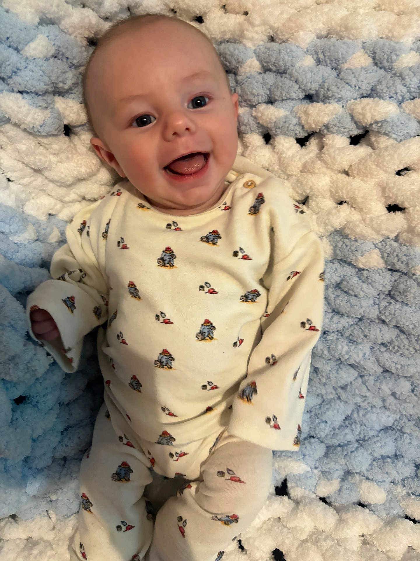Hudson is registered to the contest to win money with this photo: baby, smiling, pajamas, infant, blanket, blue, white, cute, happy, lying_down, face, child, young, cozy, soft, patterned_clothing, indoors, portrait, cute_expression, small