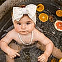 Elya a rejoint le concours — aidez-le/la à gagner de superbes lots ! baby, child, headband, bow, water, metal_tub, citrus_slices, orange, grapefruit, necklace, shell_necklace, skin, outdoor, summer, sitting, cute, portrait, infant, looking_up, playful