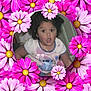 child, curly_hair, surprised_expression, tshirt, necklace, indoor, portrait, flower_frame, pink_flowers, purple_flowers, daisy, circular_frame, cute, young_child, person, casual_clothing, colorful, decorative, smiling, happy