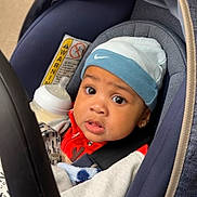 Carson joined the competition — help win amazing prizes! baby, car_seat, hat, bottle, clothing, child, face, eyes, expression, infant, jacket, person, seatbelt, baby_bottle, indoors, portrait, cute, young_child, headwear, sitting